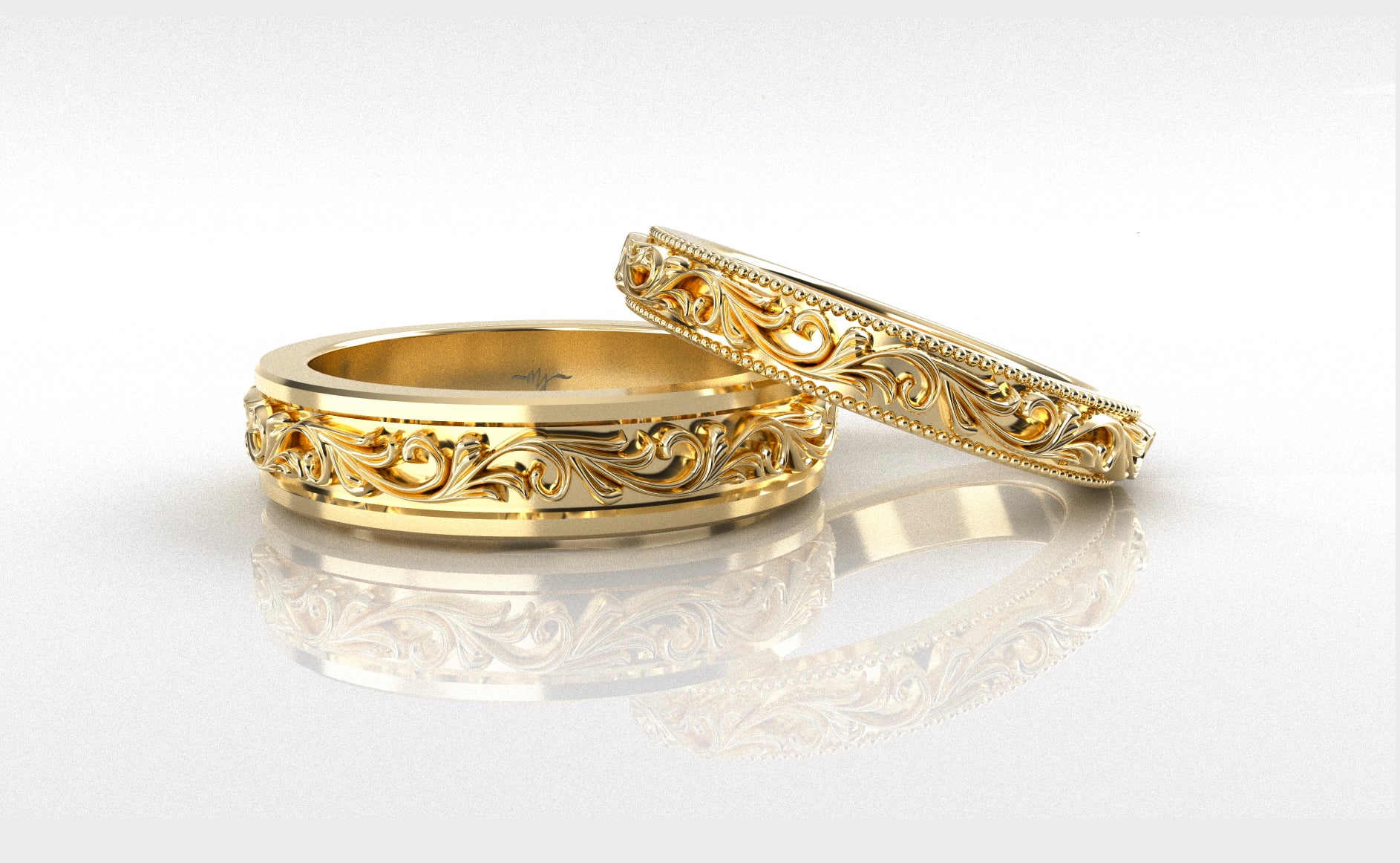 Two gold rings with intricate designs on a white background